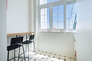 A room with a window, two black chairs, a wooden table, and patterned floor tiles. - GuestReady-Charming 3-Bedroom Lisbon Retreat (Lisbon)