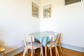 Een eetgedeelte met een ronde tafel, vier stoelen en twee ingelijste foto's aan de muur.