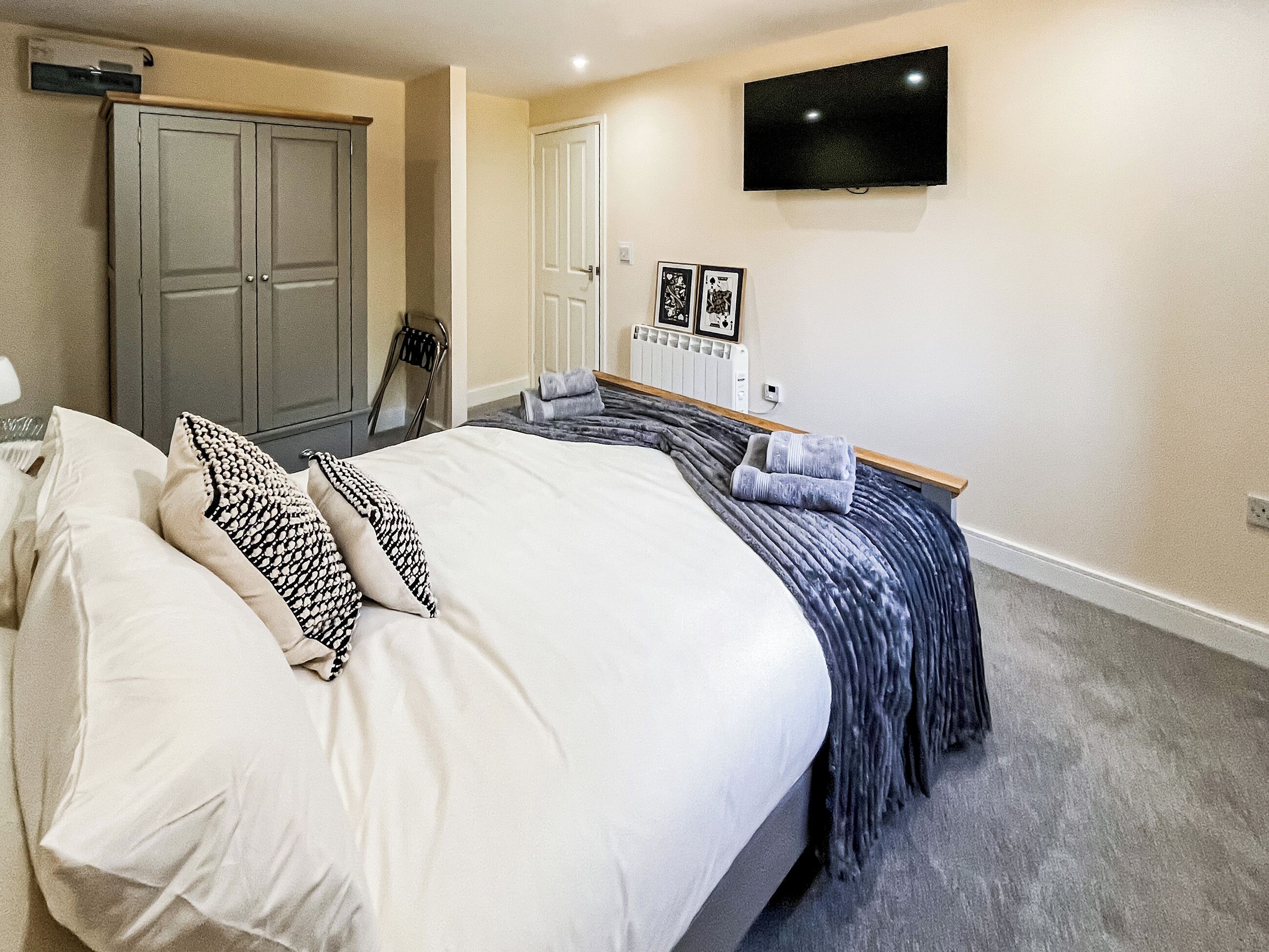 Une chambre à coucher comprenant un lit, une armoire, un radiateur, un téléviseur et une chaise.