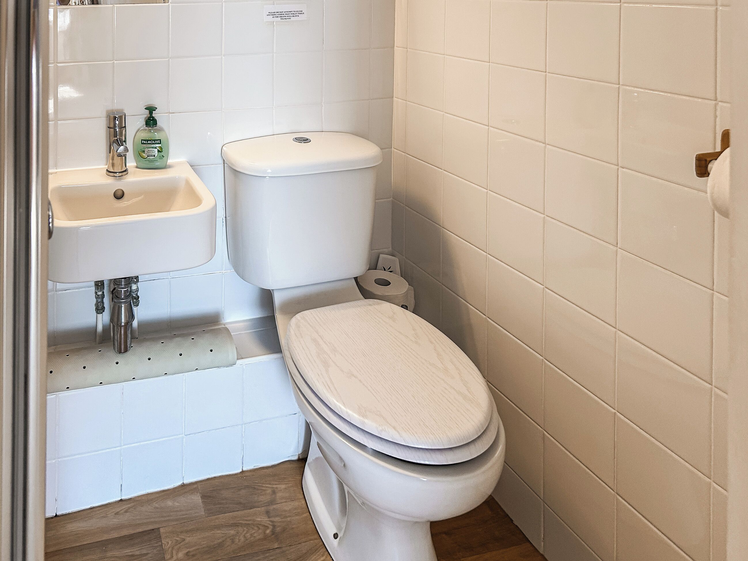 A bathroom with a toilet, a sink, and a toilet paper holder.