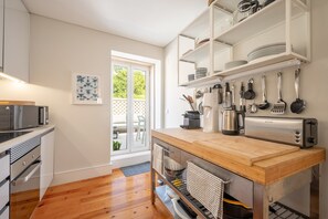 Eine moderne Küche mit Holztischplatte, Edelstahlgeräten und Blick ins Freie.