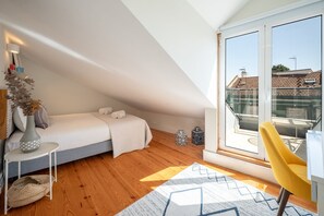 Ein modernes Schlafzimmer im Loft-Stil mit schrägem Dach, großem Fenster, Bett, gelbem Sessel und einem kleinen Tisch mit einer Vase.