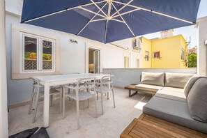 Eine Außenpatio mit Tisch und Stühlen, einer Sitzecke und einem großen Sonnenschirm.