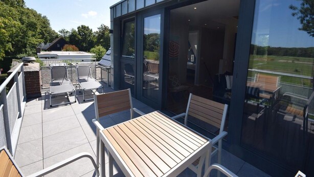 An outdoor patio with a table and chairs, a grill, and a view of the surrounding landscape. - Coastal Apartment in Oostkapelle (Oostkapelle)