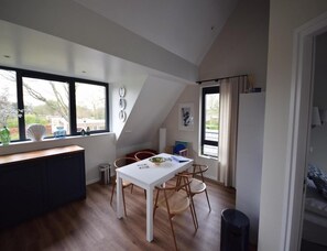Eine moderne Küche mit einem weißen Tisch, Holzstühlen und großen Fenstern.