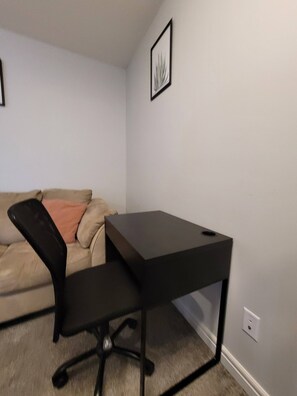 A room with a black desk, a beige sofa, and a framed picture on the wall. - Rapperswill Serenity (Edmonton)