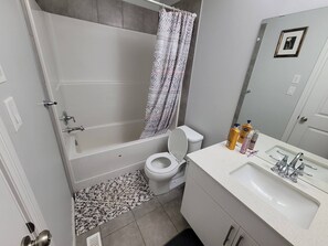 Un baño con bañera, inodoro, lavabo y cortina de ducha.