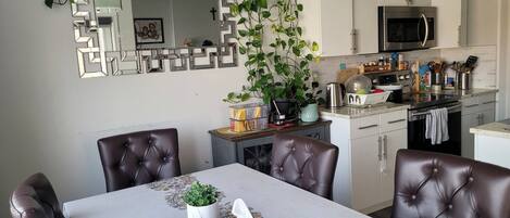 A dining area with a table, chairs, and a kitchen in the background.