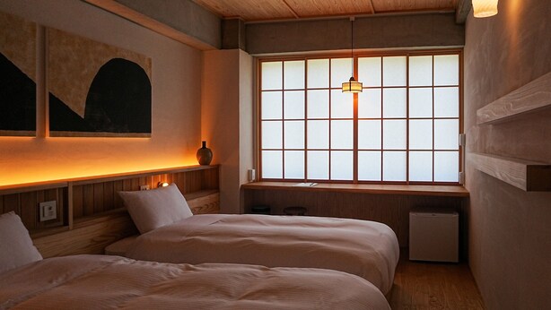 Una habitación con dos camas, techo de madera, ventana con diseño de cuadrícula y lámpara colgante.