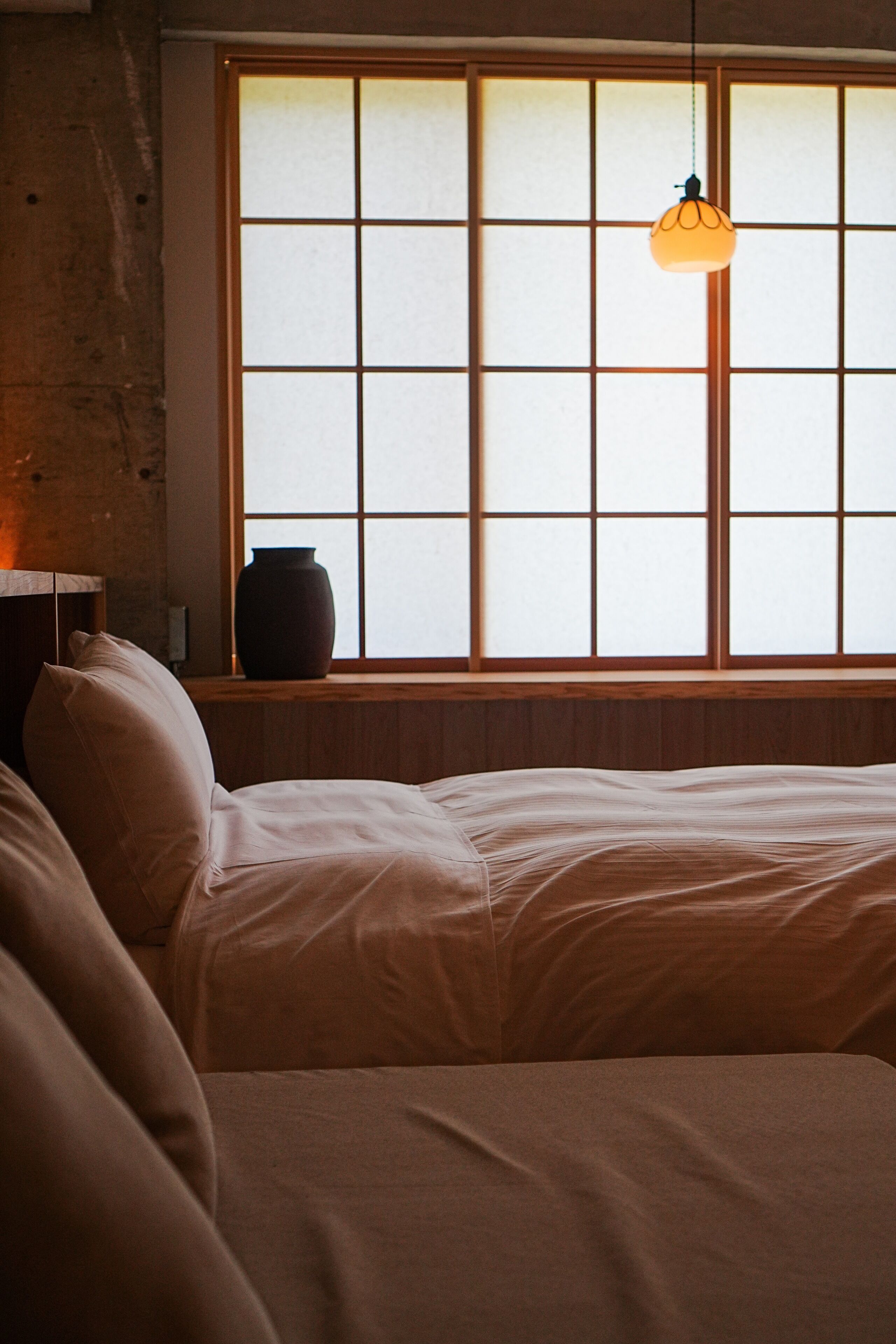 A room with a bed, a window with a view, and a hanging light fixture.