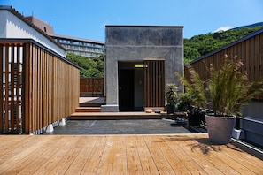 A rooftop terrace with a wooden deck, a concrete structure, and potted plants. - HAKONE CALLING (Hakone)