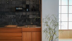 Una cocina moderna con protector de encimera oscuro, armarios de madera y una planta en el alféizar.