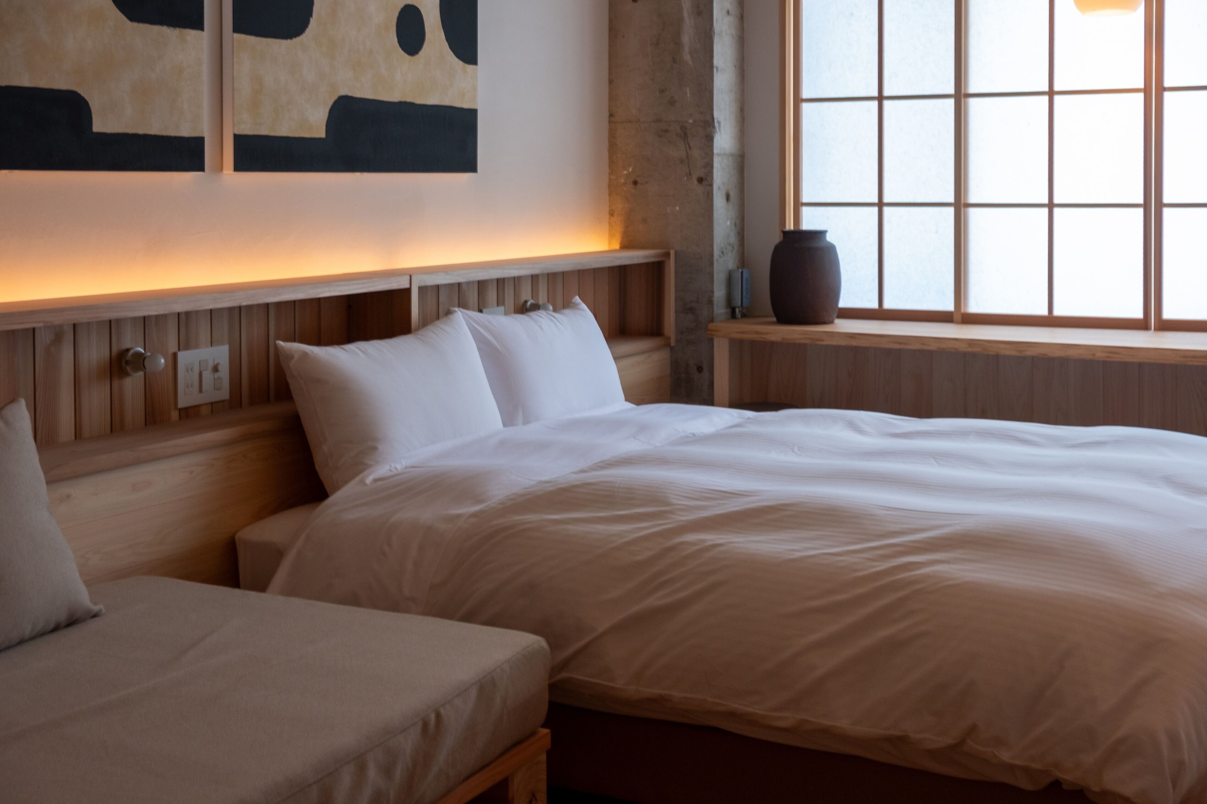 Un dormitorio con una cama grande, una cama más pequeña y una ventana con vistas.
