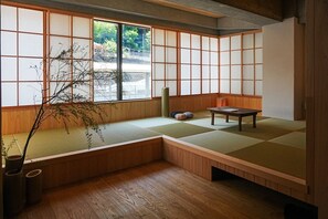 A traditional Japanese room with tatami flooring, a low table, cushions, and a view through shoji screens. - HAKONE CALLING (Hakone)