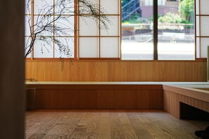 A room with wooden paneling, a large window with a view of the outside, and a bench along the wall. - HAKONE CALLING (Hakone)