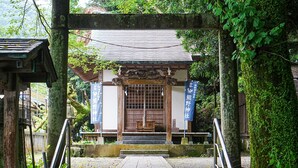 Un edificio japonés tradicional con una entrada de madera y un camino de piedra que conduce a él.
