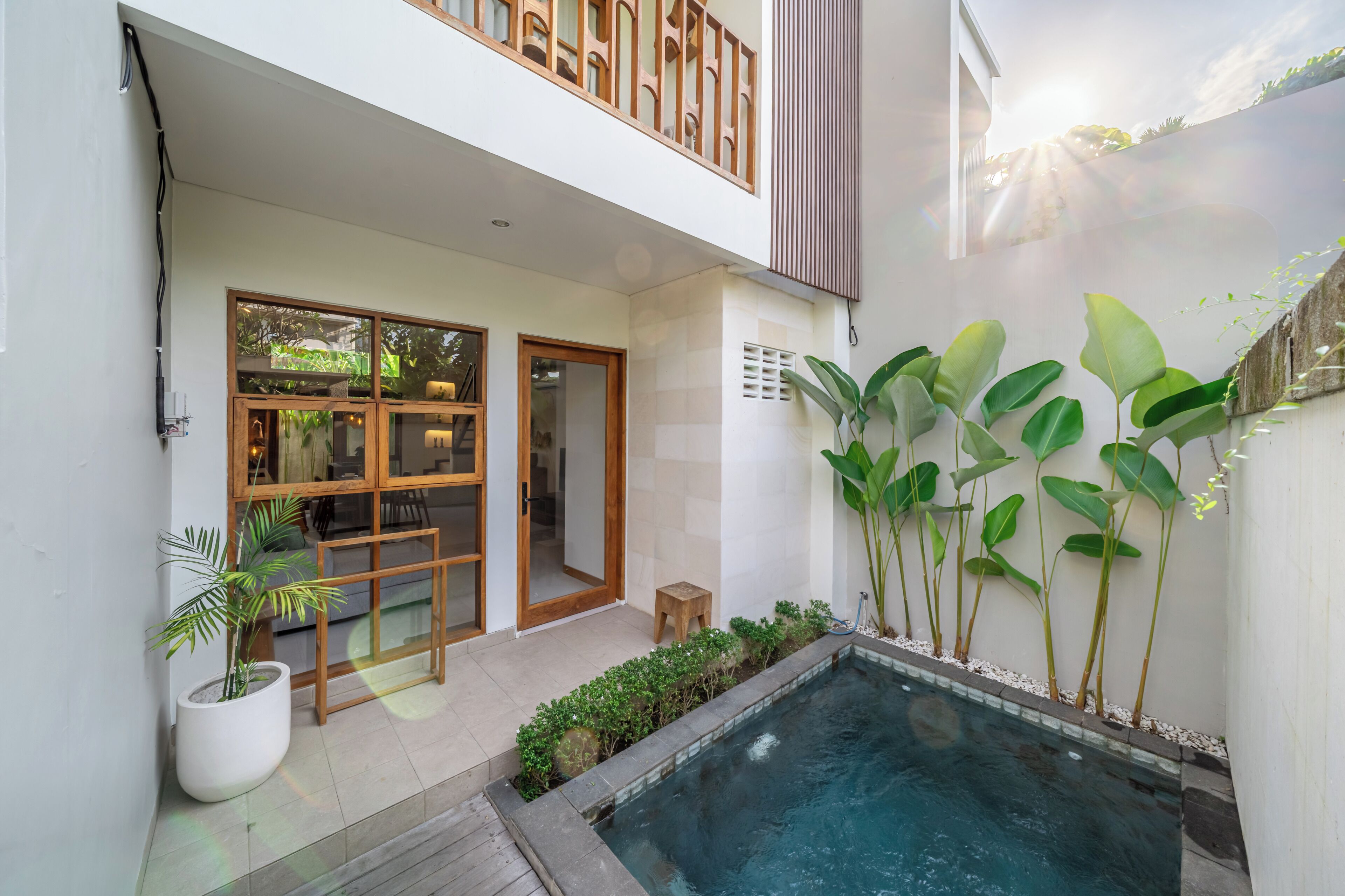 Una casa moderna con piscina, balcón de madera y plantas en macetas.
