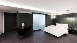 Et hotelværelse med en seng, et skrivebord og en stol.