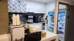 Una cocina equipada con cafetera, refrigerador y microondas.