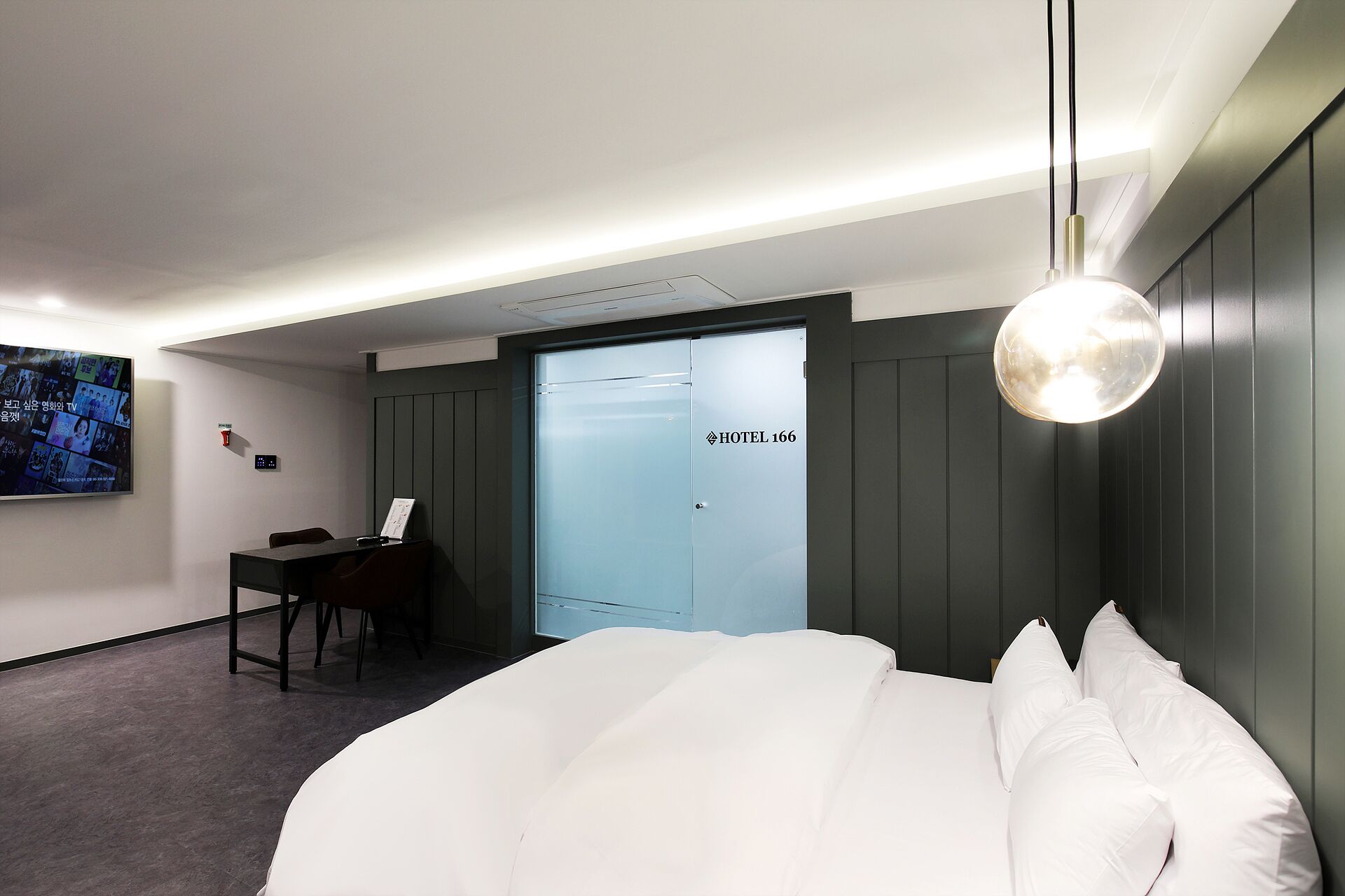 Una habitación de hotel moderna con una cama, un escritorio y una televisión mostrando varios canales.