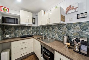 A kitchen with white cabinets, a microwave, a coffee maker, and a toaster. - Beachfront Burleigh Getaway! (Gold Coast)