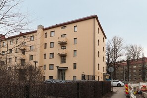 En flereetagers boligbygning med altaner, en lukket indgang og en parkeret bil.