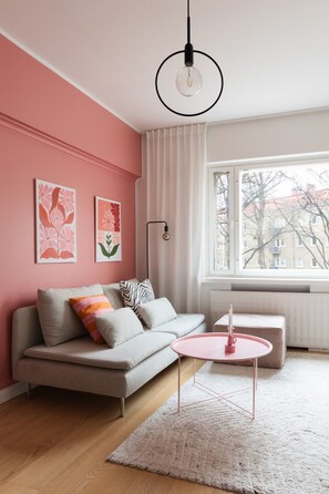 En moderne stue med en sofa, et rundt pink sofabord og en gulvlampe.