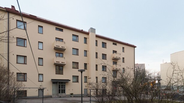 Een meerlaags woongebouw met balkons, een centrale ingang en een kleine binnenplaats.