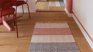 Een moderne keuken met witte kastjes, een roze aanrecht en een zichtbare kookplaat.