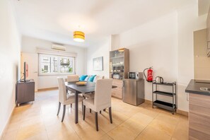 Eine moderne Küche mit Essbereich, einem Kühlschrank, einer Mikrowelle, einer Kaffeemaschine und einem Feuerlöscher.