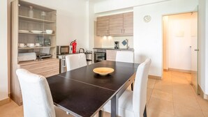 A modern kitchen with a dining table, chairs, and a glass-fronted cabinet with dishes. - GuestReady - Almirante Avenue (Lisbon)