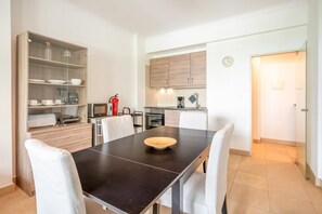 A modern kitchen with a dining table, chairs, and a glass-fronted cabinet with dishes. - GuestReady - Almirante Avenue (Lisbon)