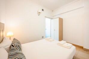 Ein Hotelzimmer mit Bett, Nachttischlampe, Spiegel und Tür.
