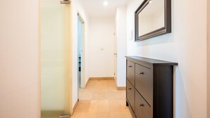 A hallway with a sliding glass door, a dark wooden dresser, and a mirror on the wall. - GuestReady - Almirante Avenue (Lisbon)