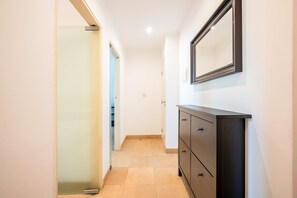 A hallway with a sliding glass door, a dark wooden dresser, and a mirror on the wall. - GuestReady - Almirante Avenue (Lisbon)