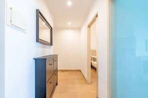 A narrow hallway with a dark blue dresser, a mirror, and a bed in the background. - GuestReady - Almirante Avenue (Lisbon)