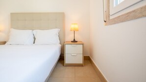 A bedroom with a bed, a nightstand with a lamp, and a window. - GuestReady - Almirante Avenue (Lisbon)
