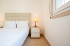 A bedroom with a bed, a nightstand with a lamp, and a window. - GuestReady - Almirante Avenue (Lisbon)