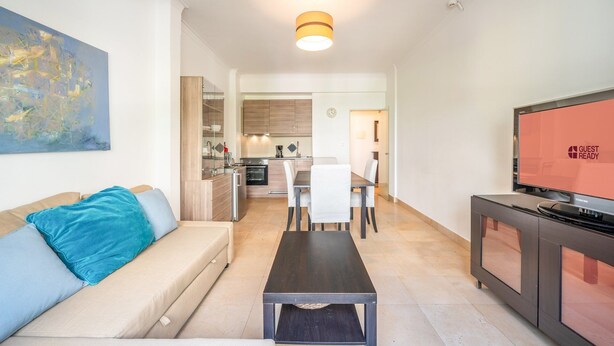 A modern living room with a sofa, a coffee table, a TV, and a kitchen in the background. - GuestReady - Almirante Avenue (Lisbon)
