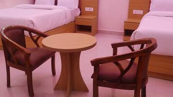 A hotel room with two beds, a round table, and two wooden chairs.
