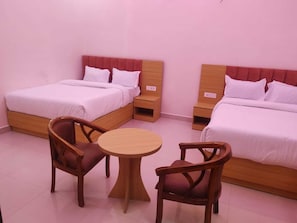 A hotel room with two beds, a round wooden table, and two wooden chairs. - Laxmi Seva Sadan Laxmi Hotel  (Barsana)
