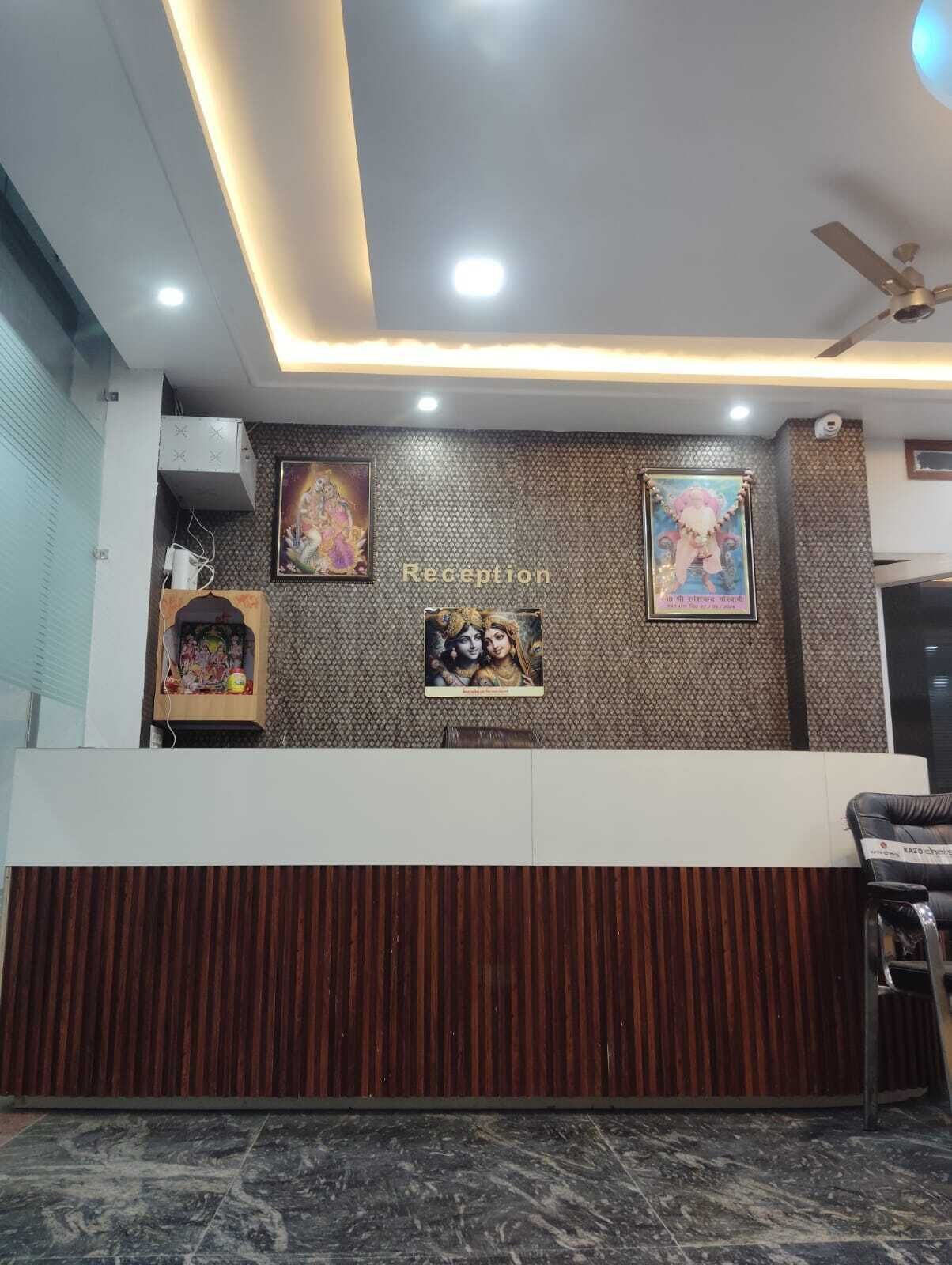 A reception area with a modern design, featuring a wooden panel wall, a ceiling fan, and framed religious posters.