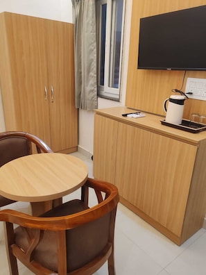 A compact kitchen with a wooden cabinet, a small round table, and a chair. - Laxmi Seva Sadan Laxmi Hotel  (Barsana)