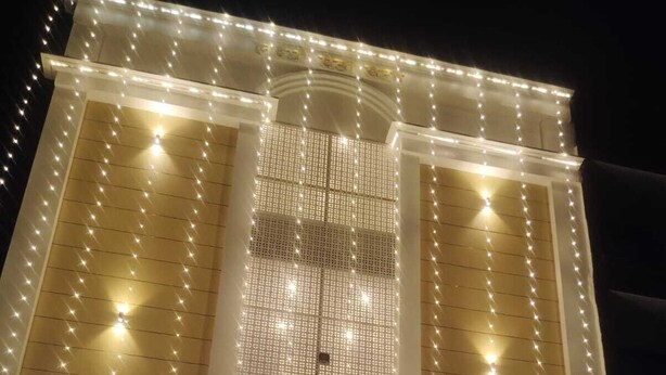 A hotel facade with a decorative light display and a sign in a non-English script. - Laxmi Seva Sadan Laxmi Hotel  (Barsana)