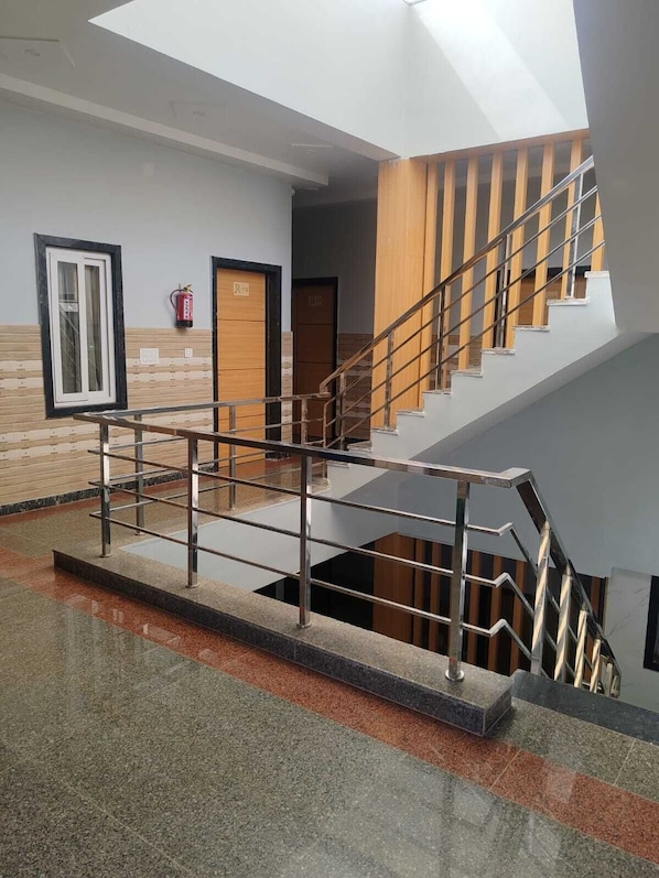 A modern interior with a staircase, a fire extinguisher, and a door labeled 'Robe'. - Laxmi Seva Sadan Laxmi Hotel  (Barsana)