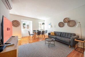 A living room with a sofa, a coffee table, a TV, and a dining area with chairs and a table. - GuestReady - Charming Apartment in Lisbon 3E (Lisbon)