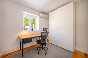 Ein kleiner Büroraum mit Schreibtisch, Stuhl und Fenster.