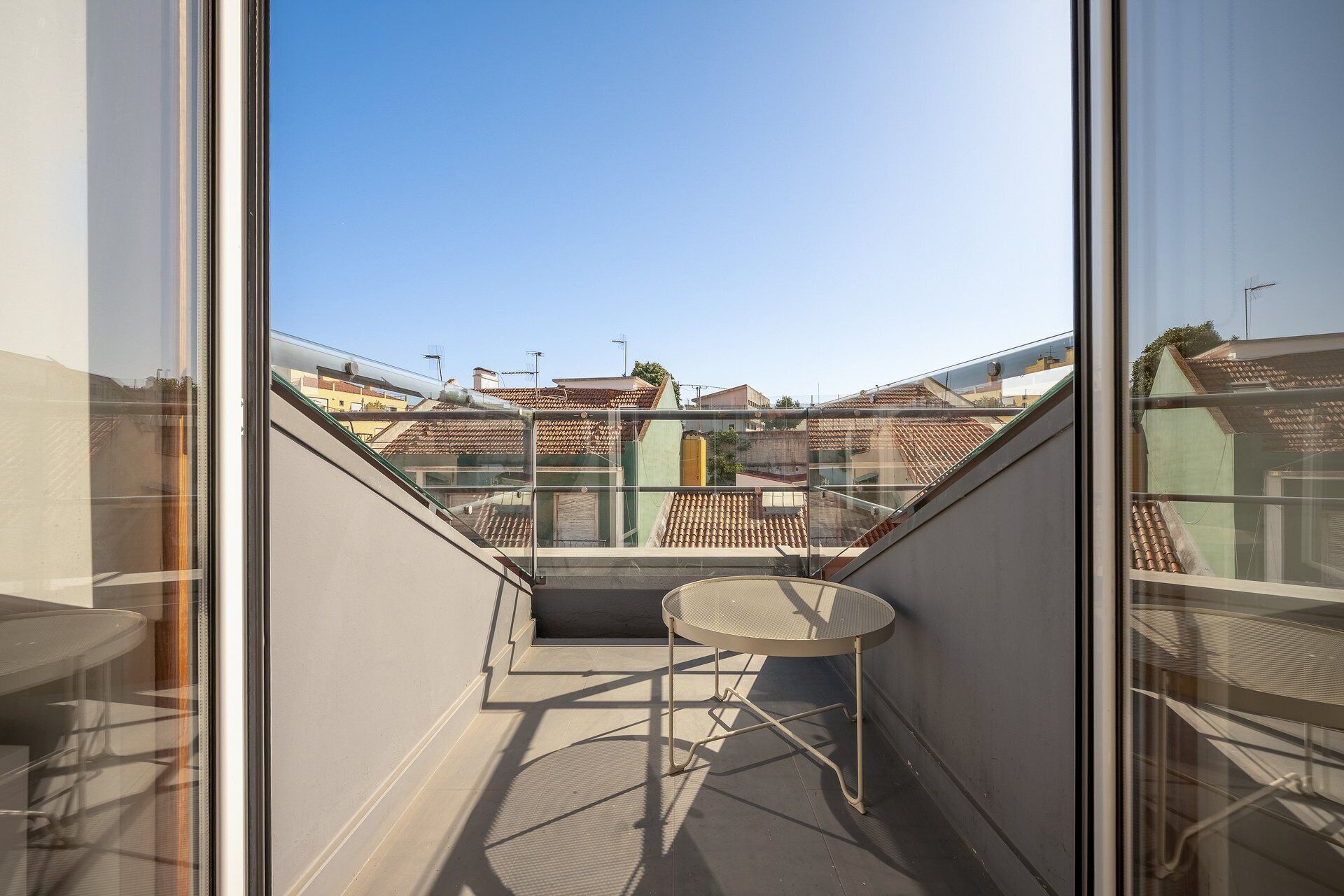 Un balcon avec une table et des chaises, une vue dégagée sur le paysage urbain et une rambarde en verre.