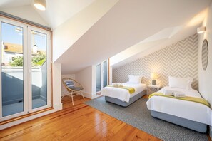 A modern hotel room with two beds, a balcony, and a herringbone-patterned wall. - GuestReady - Charming Apartment in Lisbon 3E (Lisbon)