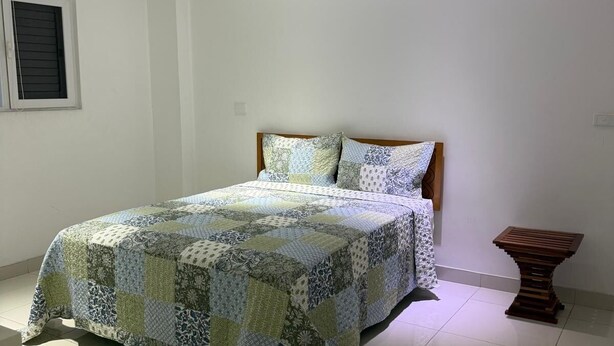 Una camera da letto con un letto, un comodino in legno e una finestra con persiane.